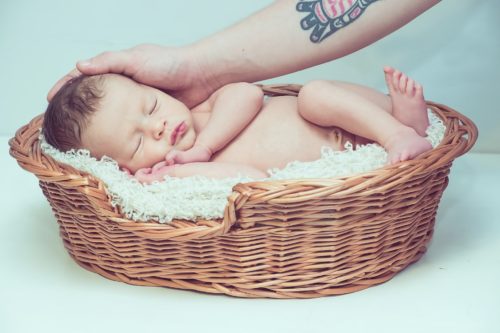 bebé en cesta de mimbre siendo acariciado